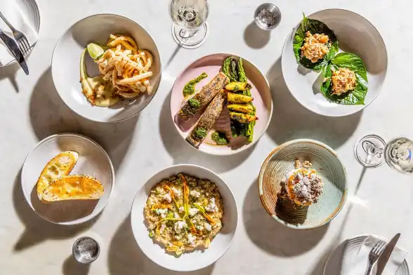 Plates of food at Love Fish including grilled fish, risotto and calamari