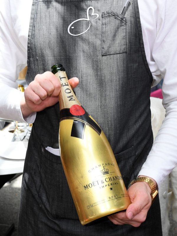Waiter with a bottle of champagne ate love.fish restaurant